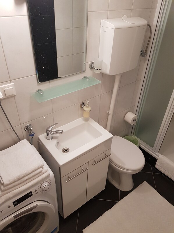 A bathroom with a sink, toilet, and washing machine. - Apartments Minerva (Dubrovnik)