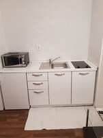 Uma cozinha compacta com micro-ondas, pia e armários.