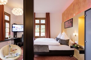 Una habitación de hotel con cama, escritorio con computadora, silla y televisión.