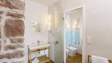 Une salle de bain avec un meuble-lavabo en bois, un évier, des toilettes et un espace douche.