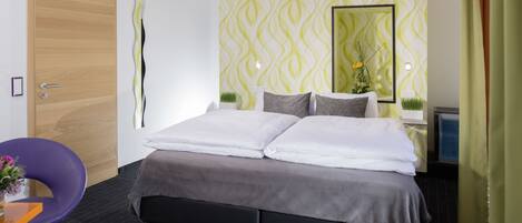 A modern hotel room with a large bed, a wooden door, and a mirror on the wall.