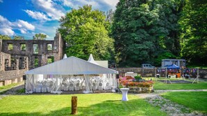 Montaje de boda con carpas en un área con césped y un edificio histórico al fondo.