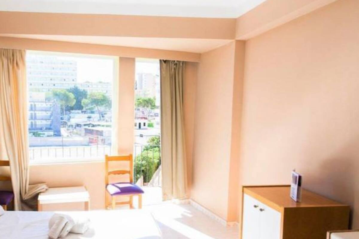 Una habitación de hotel con cama, escritorio, silla y ventana con vista a la ciudad.