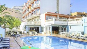 Un hotel con piscina, zona de estar al aire libre y bar.