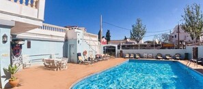 A swimming pool with lounge chairs and a small table, surrounded by buildings. - Teix (Calvia)