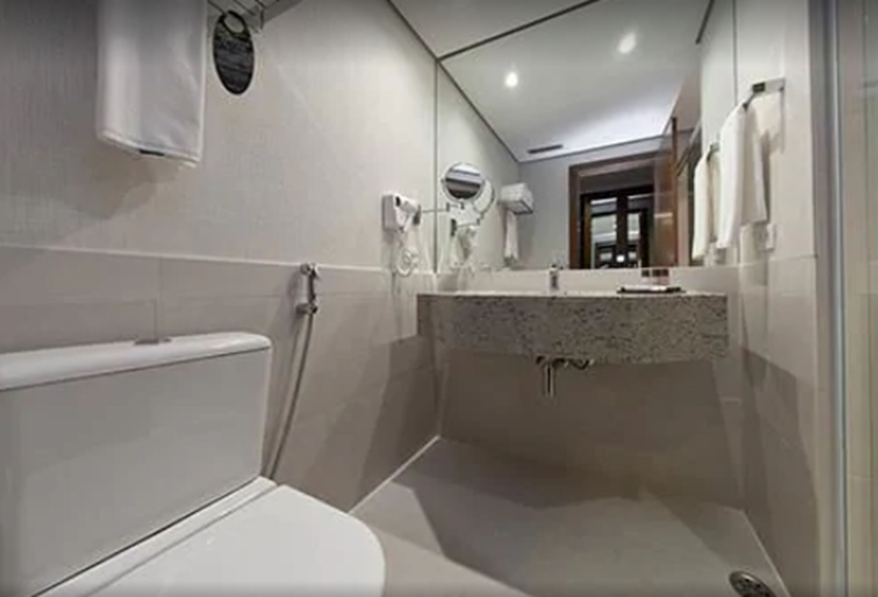 Une salle de bain moderne comprenant des toilettes, un lavabo avec un miroir et un espace douche.