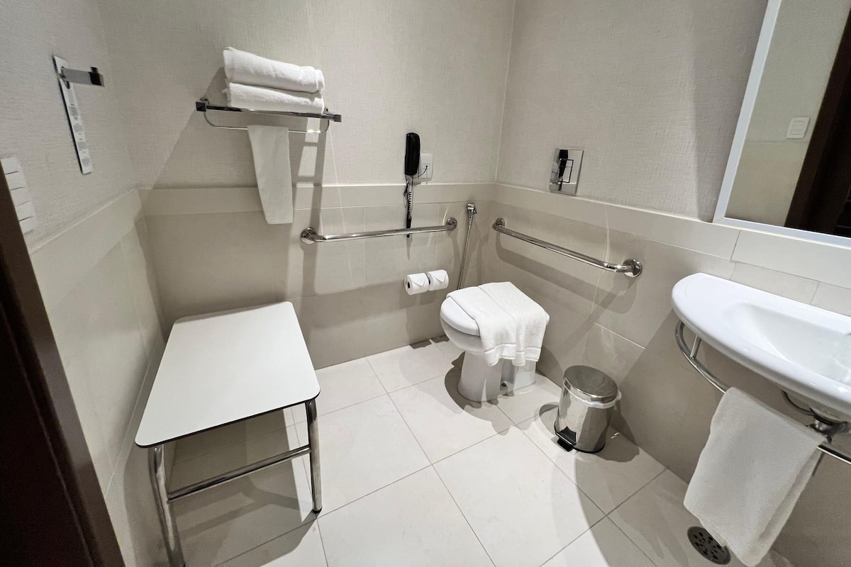 A modern bathroom with a toilet, bidet, sink, and a small table.