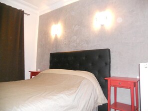 A bed with a headboard, two bedside tables, and wall-mounted lights. - Hotel Pacific (Paris)