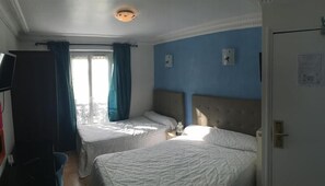 A hotel room with two beds, a TV, and a window with curtains. - Hotel Pacific (Paris)