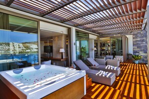 Un área de descanso al aire libre moderna con terraza de madera, jacuzzi y asientos.