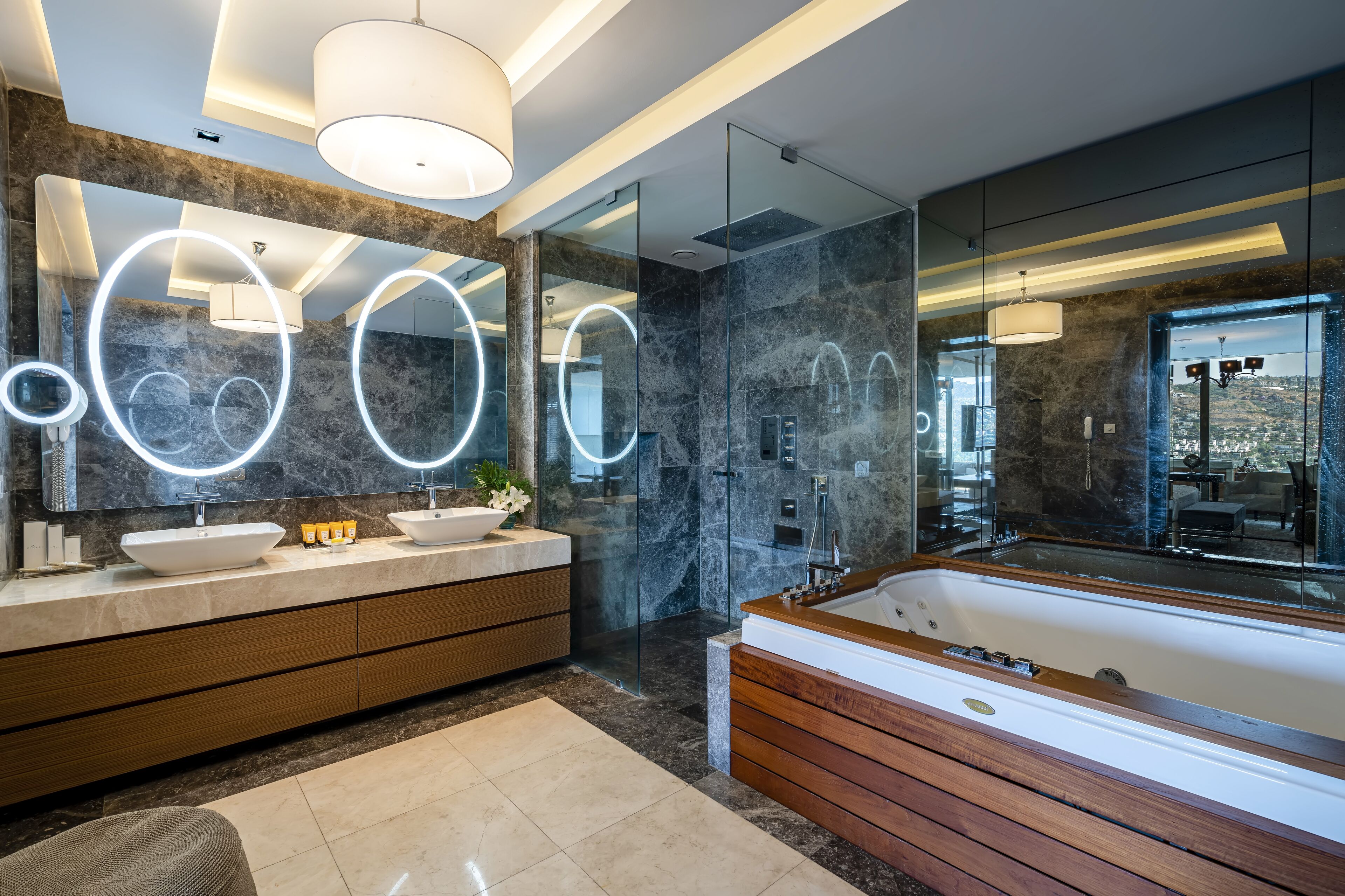 A modern bathroom with a large mirror, two sinks, a bathtub, and a glass shower enclosure.
