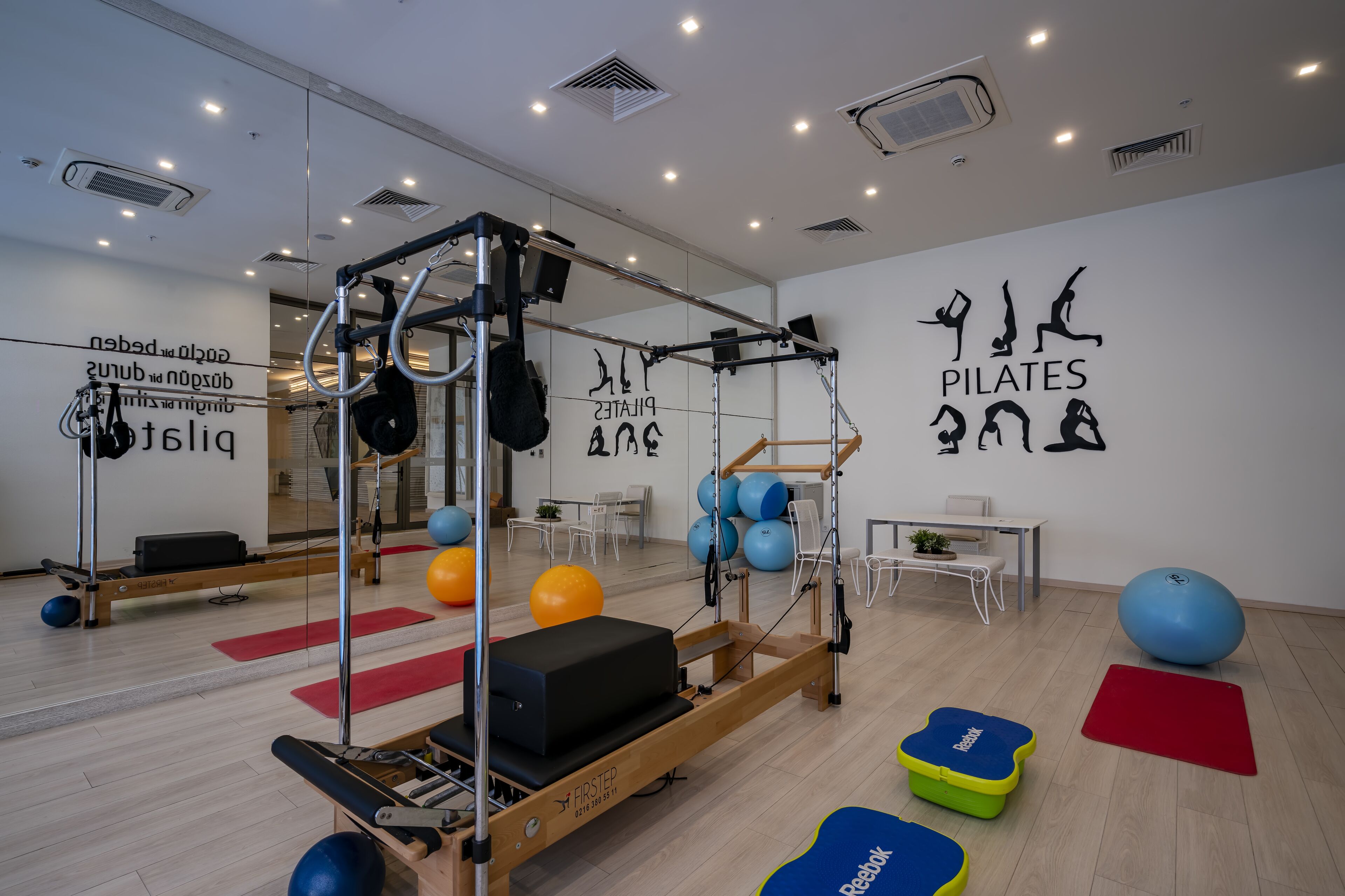 Un estudio de Pilates con equipo de ejercicio, colchonetas y un espejo grande.