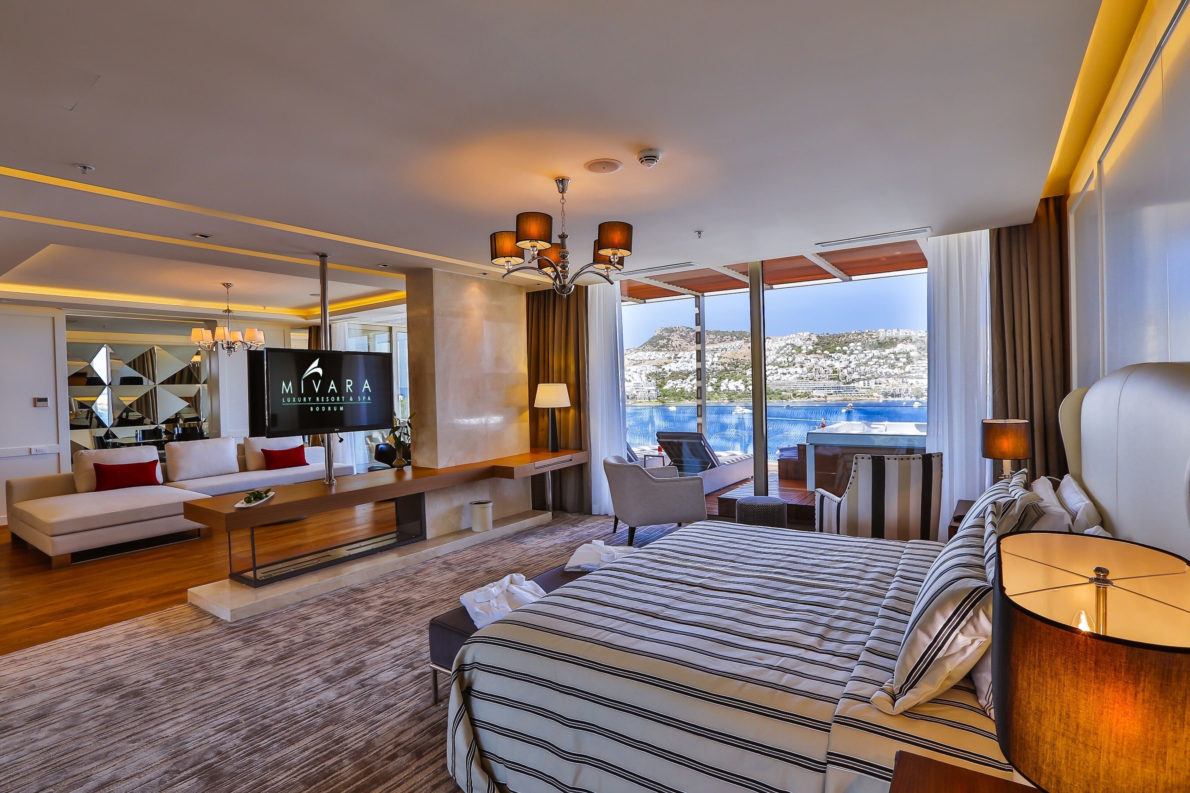 Una habitación de hotel moderna con una cama grande, televisión, sofá y zona de comedor.