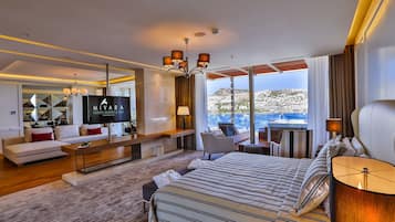 Una habitación de hotel moderna con una cama grande, televisión, sofá y zona de comedor.
