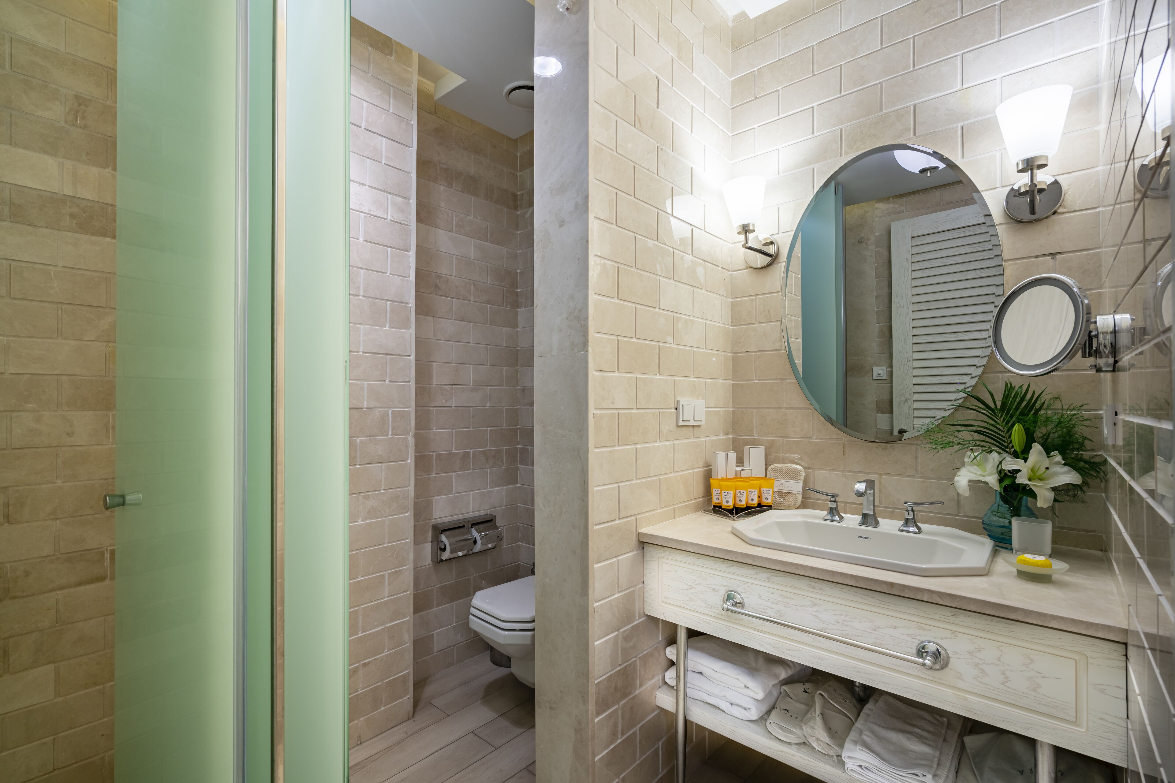A bathroom with a shower, toilet, sink, mirror, and towel rack.