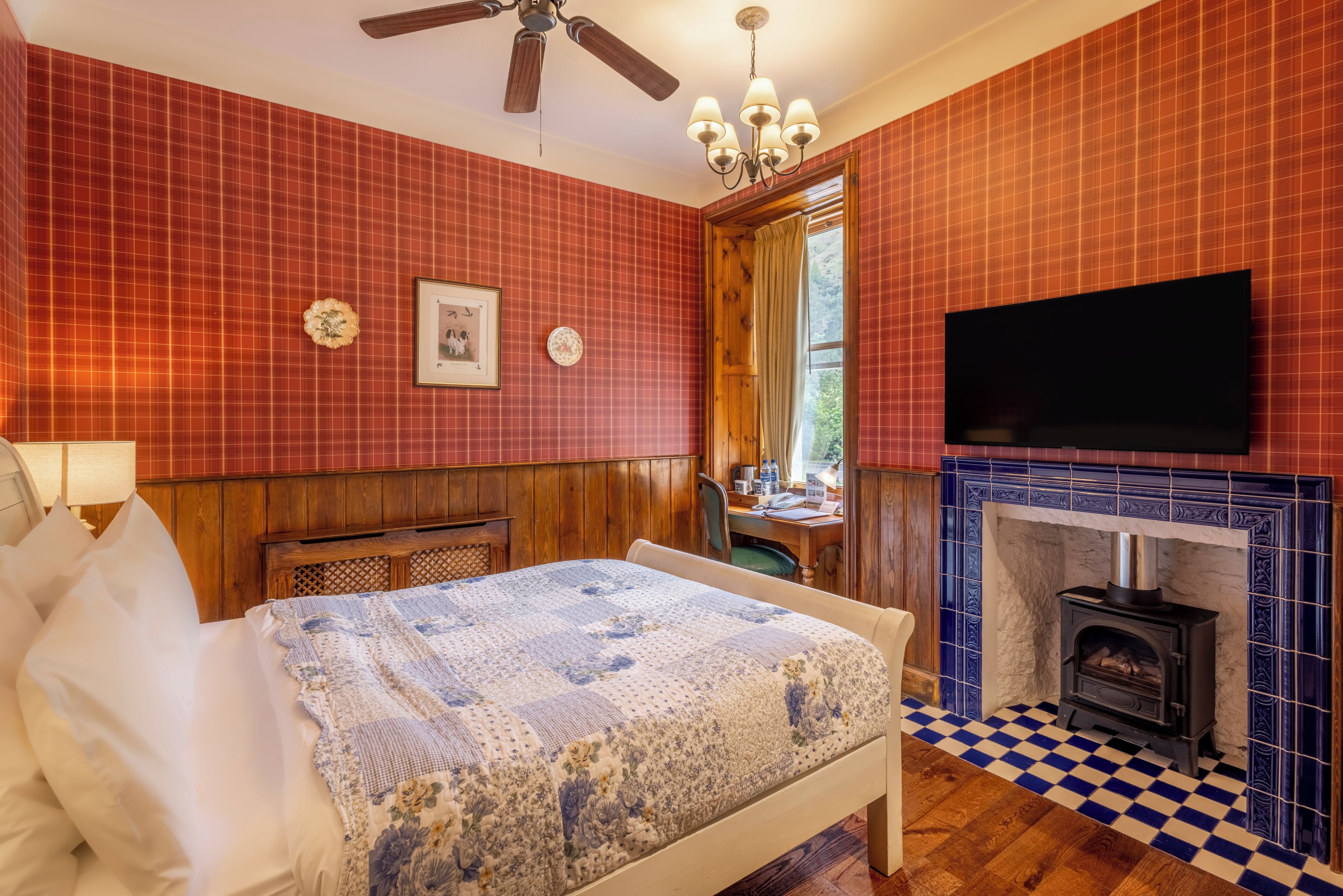 Un dormitorio con una cama, televisor, chimenea y ventana.