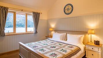 A bedroom with a bed, two bedside lamps, a nightstand, a window with curtains, and a wall-mounted compass.