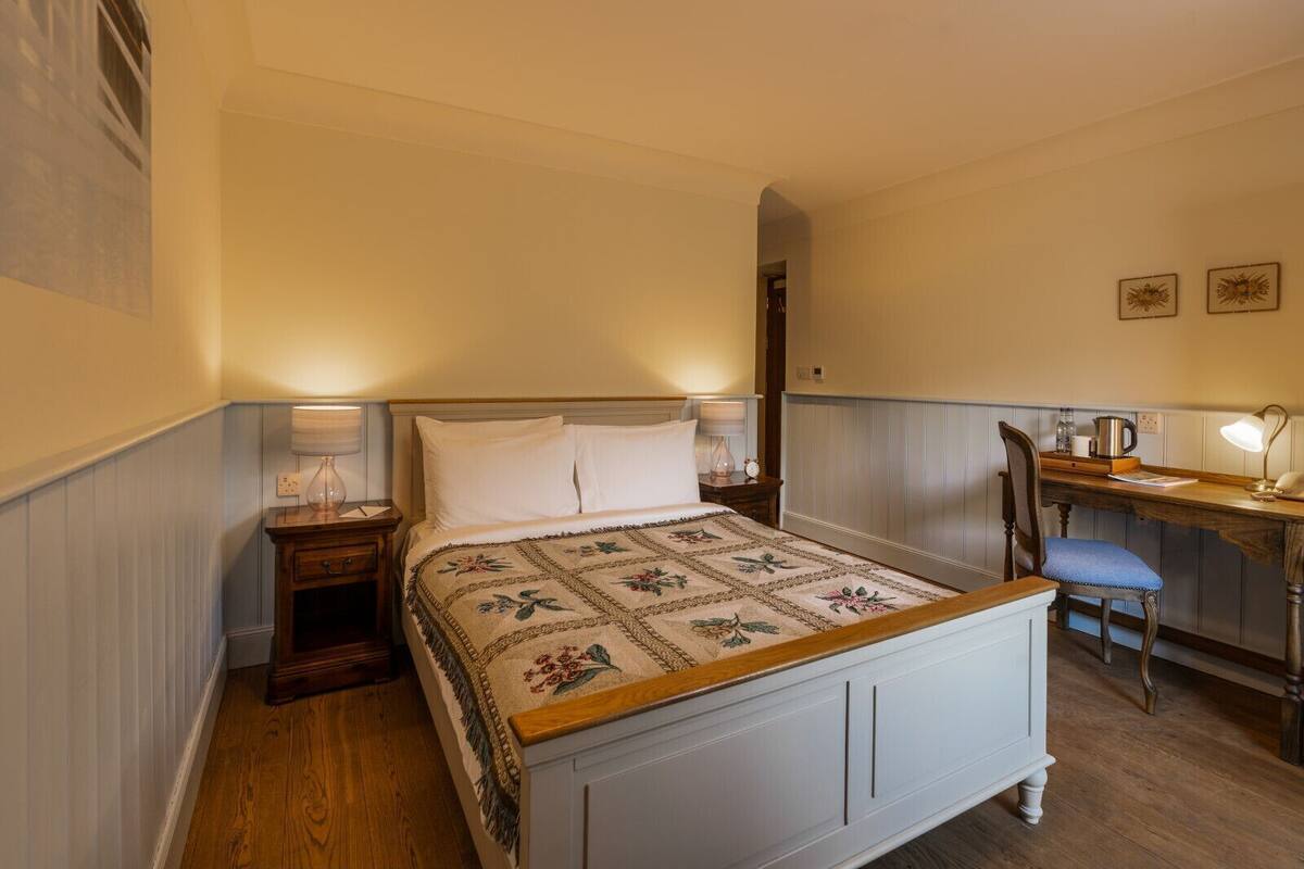 Une chambre à coucher avec un lit, des tables de chevet, un bureau et une chaise.