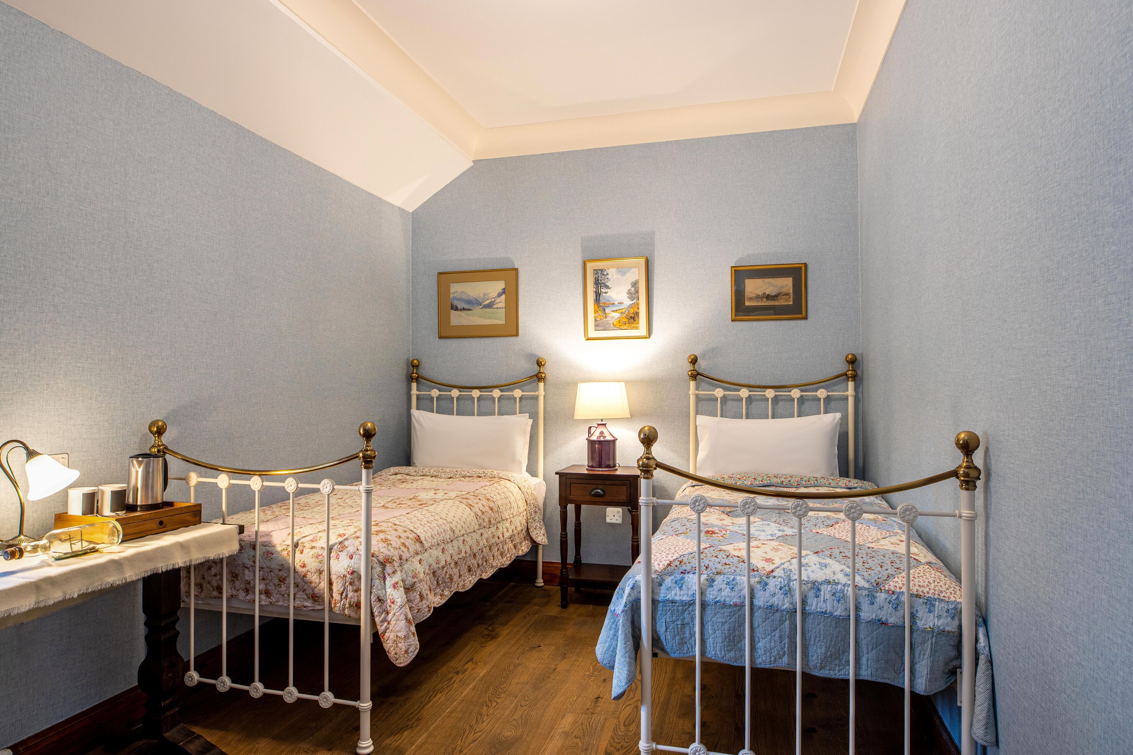 Een slaapkamer met twee eenpersoonsbedden, een nachtkastje met een lamp en een nachtkastje met een lamp.