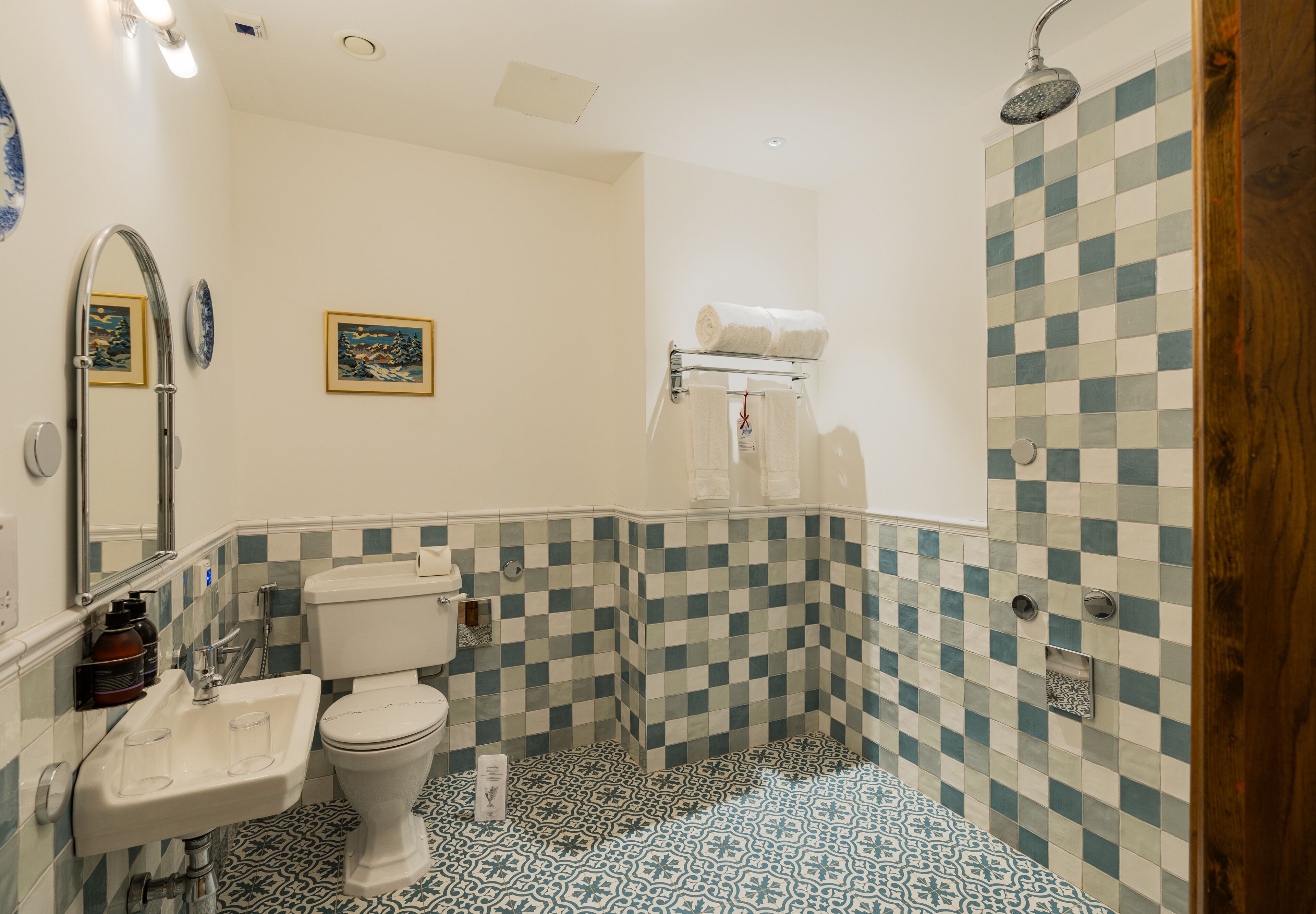 A bathroom with a checkered floor, a sink, a toilet, and a shower.