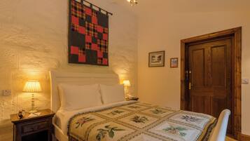 A bedroom with a bed, nightstands, a quilt, a wooden door, and a wall-mounted quilt.