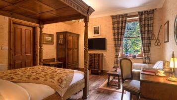 Un dormitorio tradicional con cama con dosel, muebles de madera, un escritorio con lámpara y un televisor.