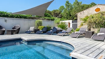 En sÀsongsöppen utomhuspool och solstolar