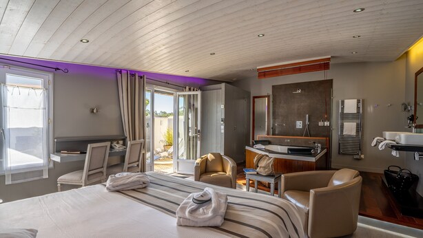 Een hotelkamer met een bed, twee stoelen, een bureau, een badkamer en uitzicht op de omgeving.