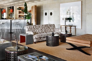 A modern living room with a patterned sofa, a coffee table, and a reading area with magazines. - The Villas at Bahia del Duque (Adeje)