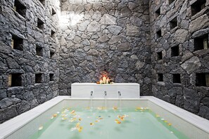 A stone-walled spa area with a rectangular pool, candles, and flower petals. - The Villas at Bahia del Duque (Adeje)