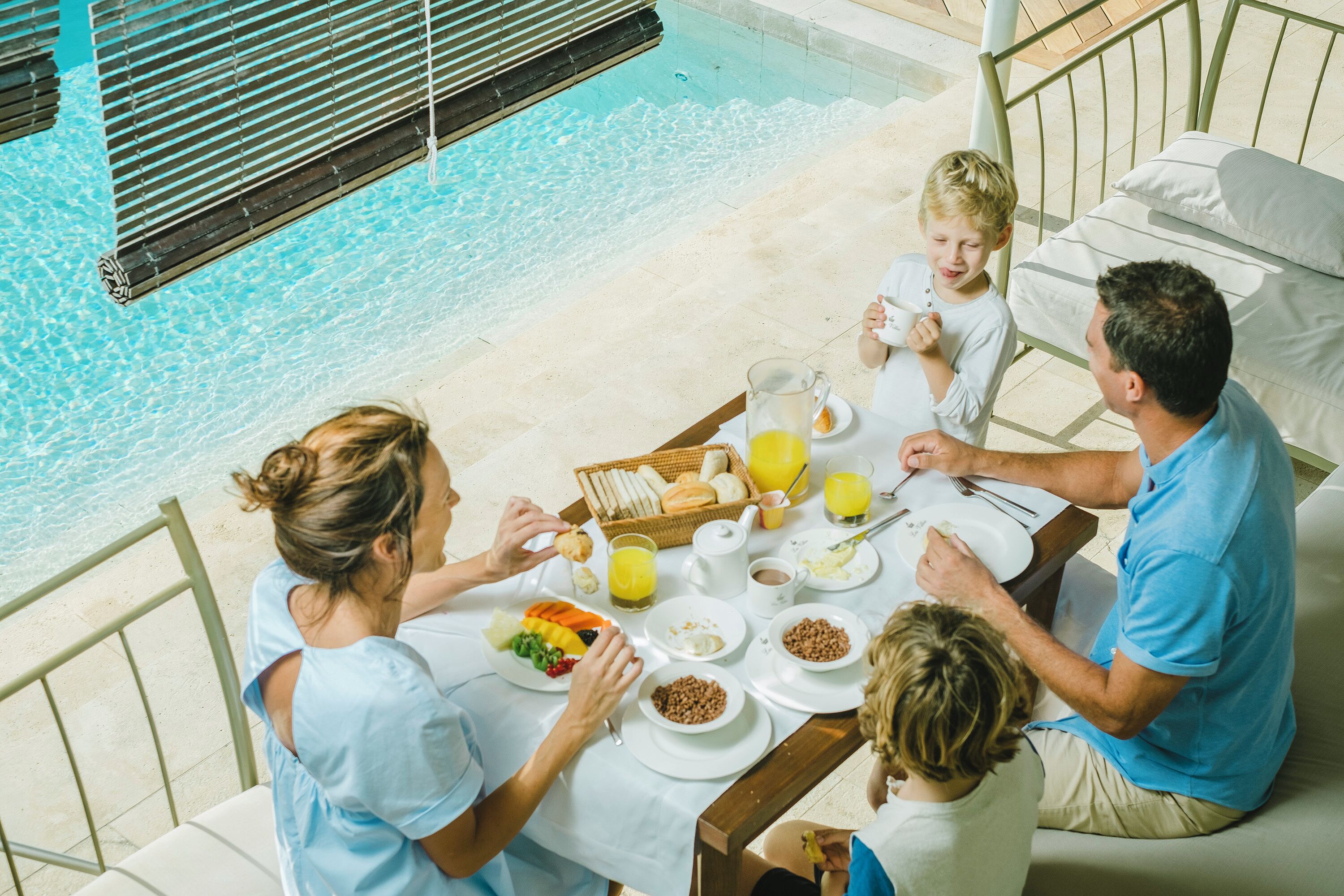 Una mesa de comedor con alimentos para el desayuno y vista a la piscina.