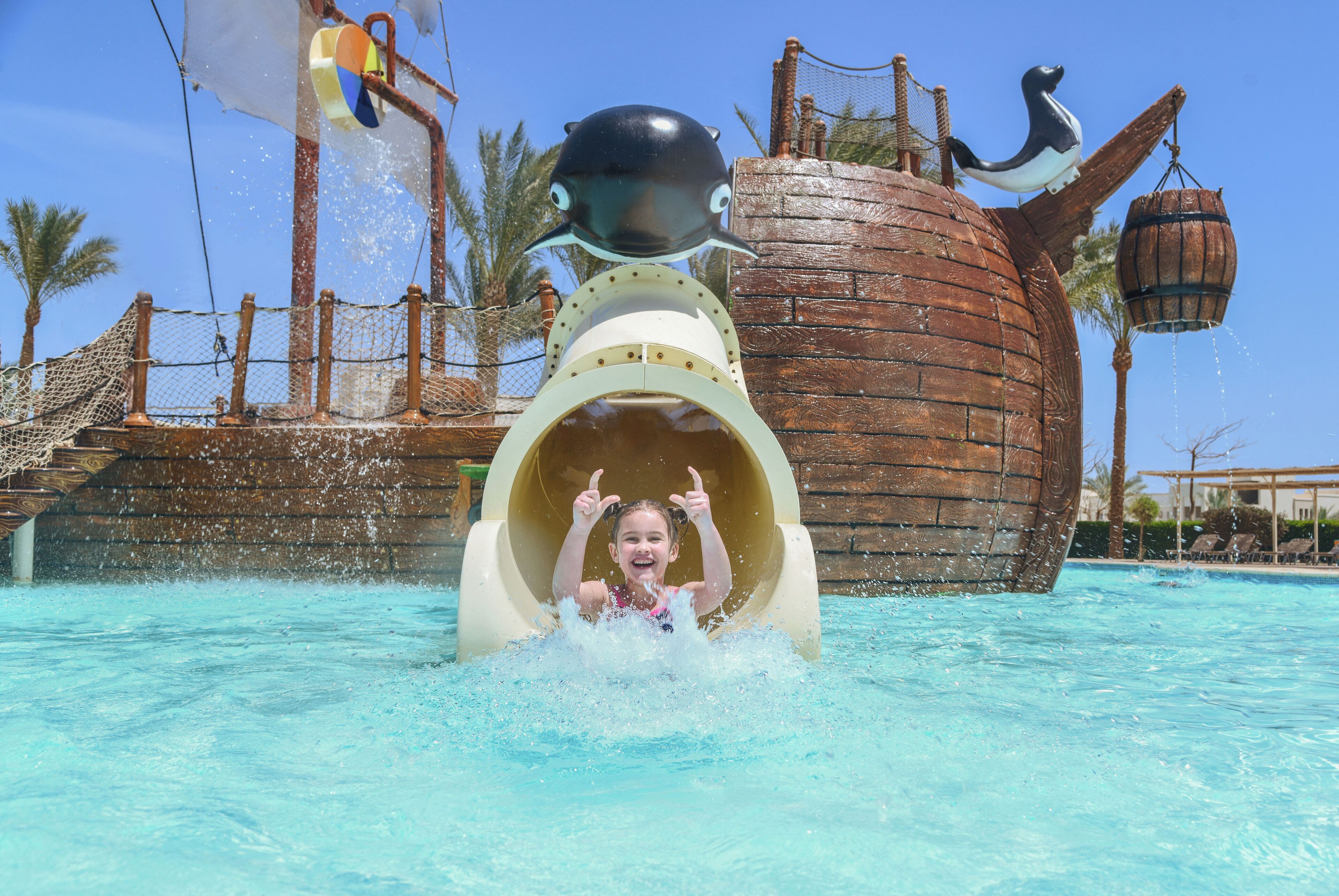 A water slide with a pirate ship theme, including a ship's wheel and a barrel.