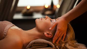 Eine Person erhält eine Massage, im Hintergrund sind Handtücher und Kerzen.