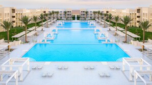A large swimming pool with multiple lanes, surrounded by lounge chairs and palm trees. - JAZ Aquaviva - All inclusive (Makadi Bay)