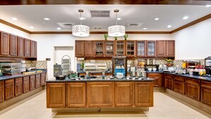 Un'ampia cucina con mobili in legno, un'isola centrale e una penisola per colazione.