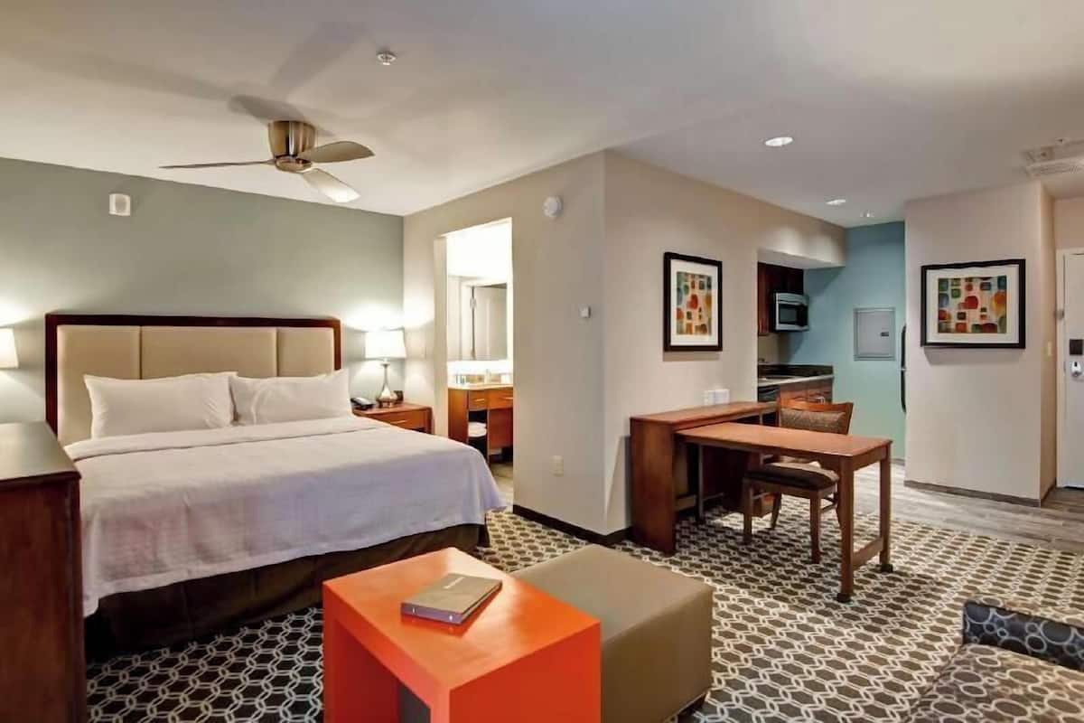 A hotel room with a bed, desk, chair, and a small table.