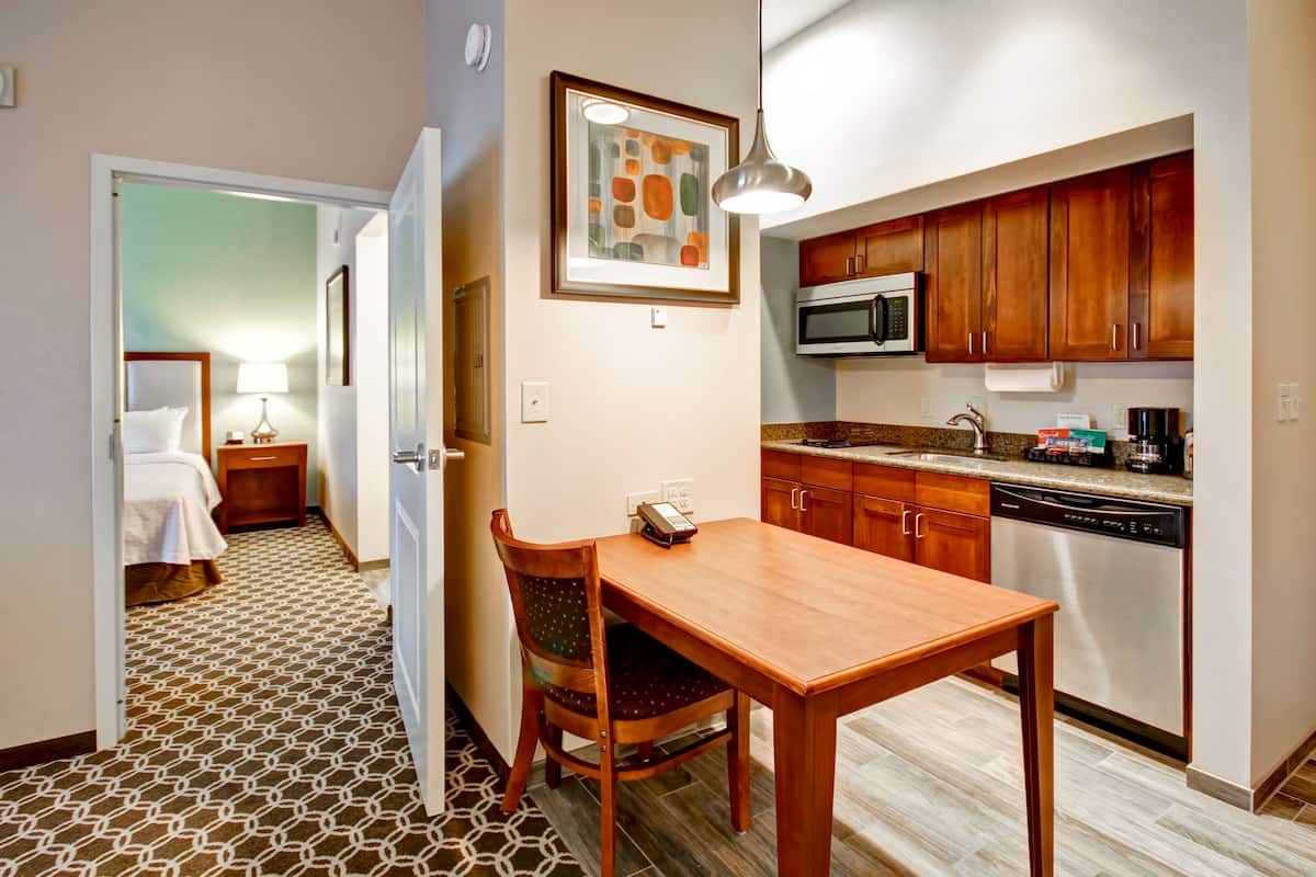 A hotel room with a dining area, kitchenette, and a bathroom.