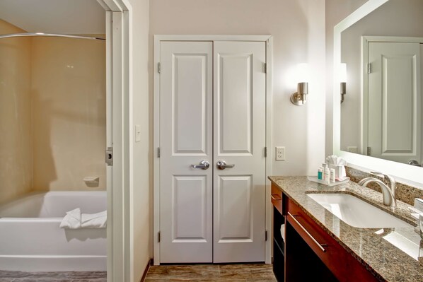 Un baño con puertas dobles, una bañera, un lavabo con encimera de granito y un espejo sobre el lavabo.