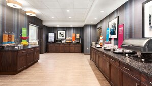 A modern hotel lobby with a central reception desk, a buffet area, and a coffee station. - Hampton Inn Kennewick at Southridge (Kennewick)