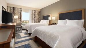 A hotel room with two beds, a desk with a television, a chair, and a view of the outdoors. - Hampton Inn Kennewick at Southridge (Kennewick)