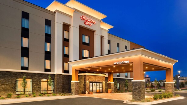 A Hampton Inn hotel with a 'Welcome' entrance, stone facade, and a clear sky at dusk. - Hampton Inn Kennewick at Southridge (Kennewick)