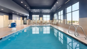 An indoor swimming pool with clear blue water, a blue chair, and a ladder. - Hampton Inn Kennewick at Southridge (Kennewick)