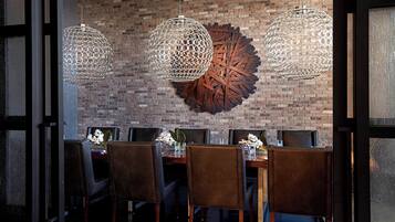 A dining area with a brick wall, three hanging spherical light fixtures, and a large decorative metal piece.