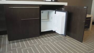 A compact kitchen with a refrigerator, a microwave, and a coffee maker on the counter.
