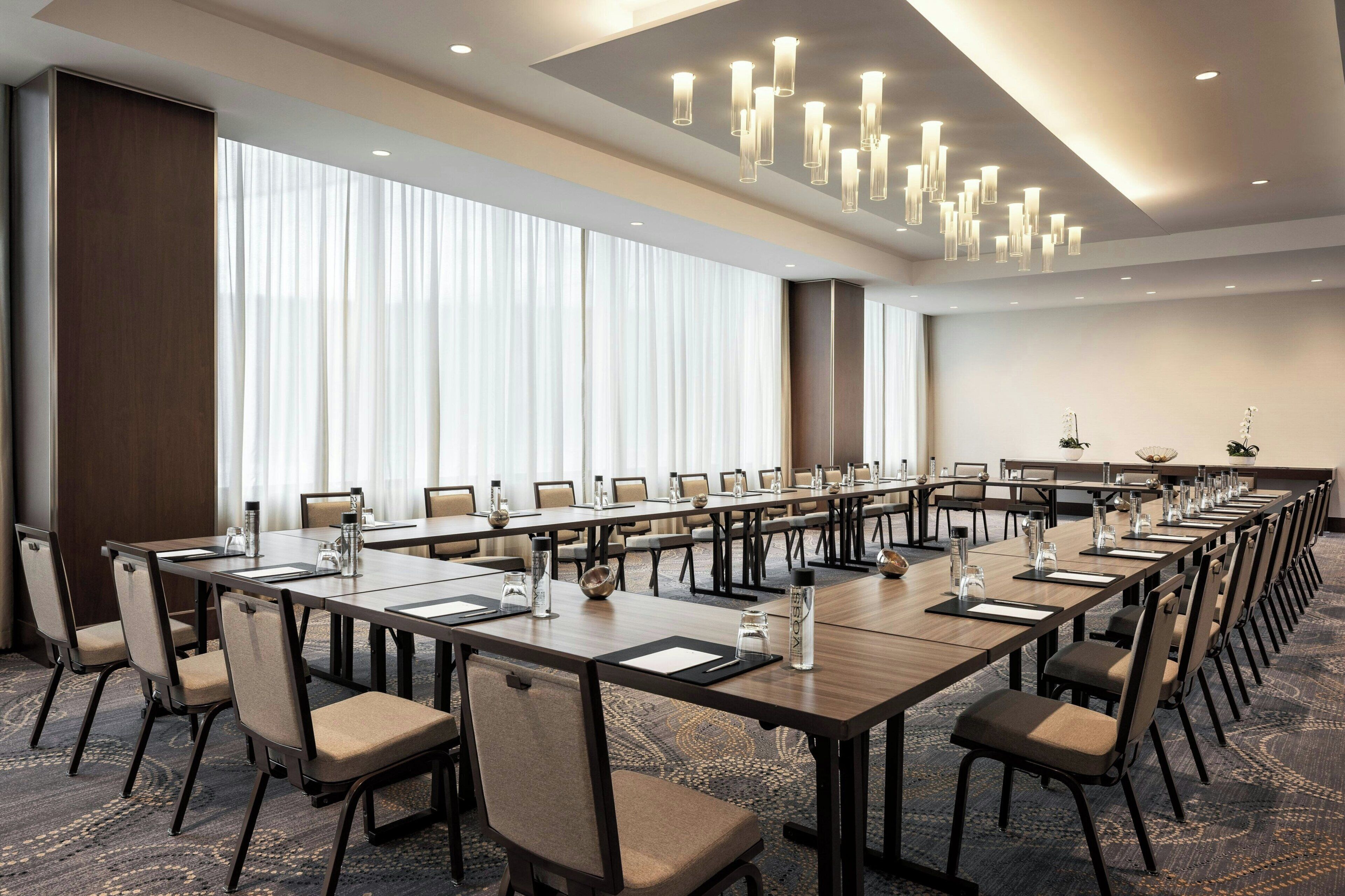A conference room with long tables, chairs, and a chandelier.