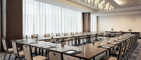 A conference room with long tables, chairs, and a chandelier.