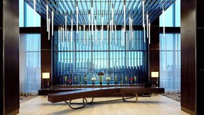 Un hall d’hôtel moderne, doté d’un long comptoir d’accueil, de grandes fenêtres et d’une vue sur le paysage urbain.