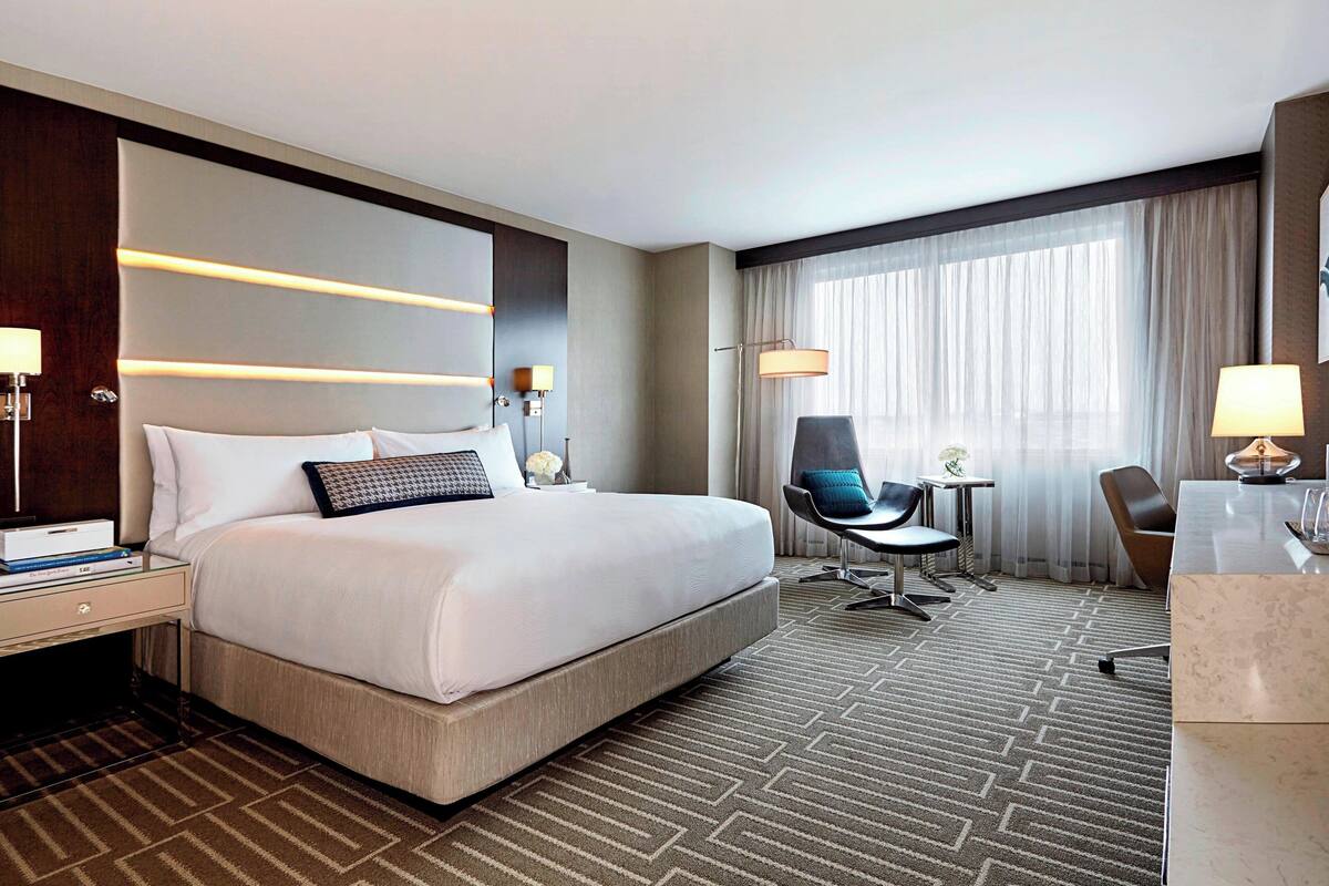 Ein Hotelzimmer mit einem großen Bett, einem Schreibtisch, einem Stuhl und einem kleinen Tisch.