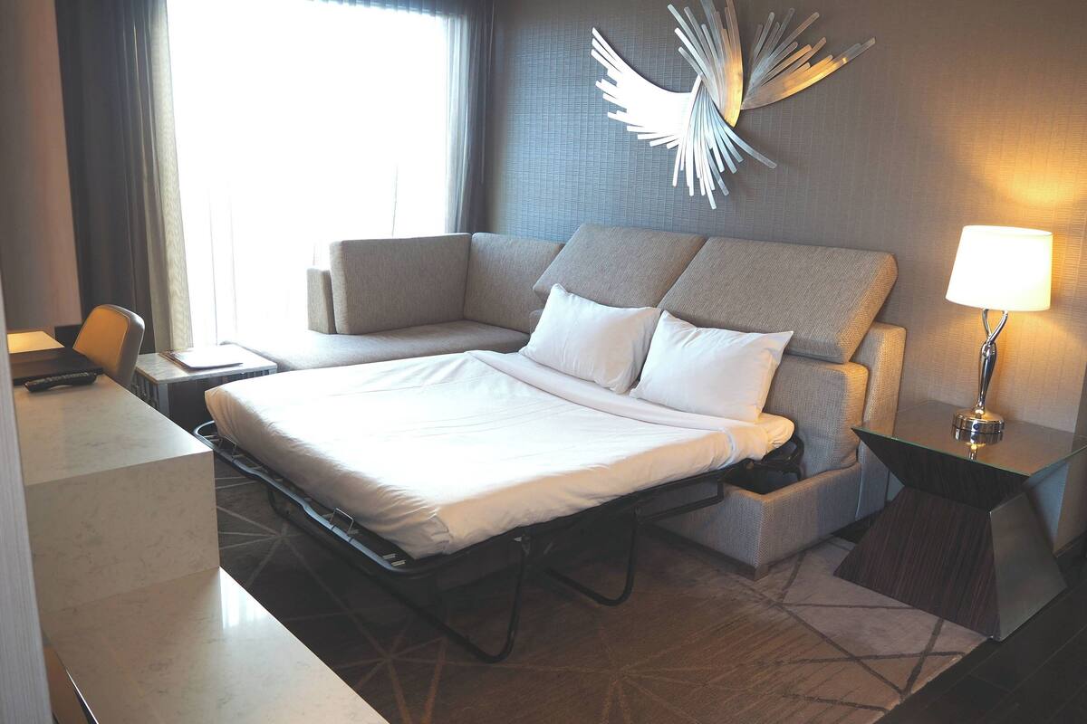 Ein Hotelzimmer mit Bett, Sofa, Schreibtisch und Lampe.