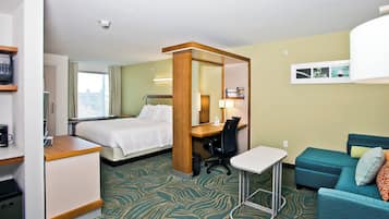 A hotel room with a bed, desk, chair, and a small table.